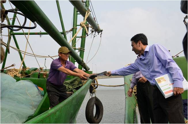 Cán bộ Chi cục Thủy sản phát tờ rơi tuyên truyền về đam bảo khai thác an toàn trên biển cho ngư dân tại cảng cá Cửa Việt